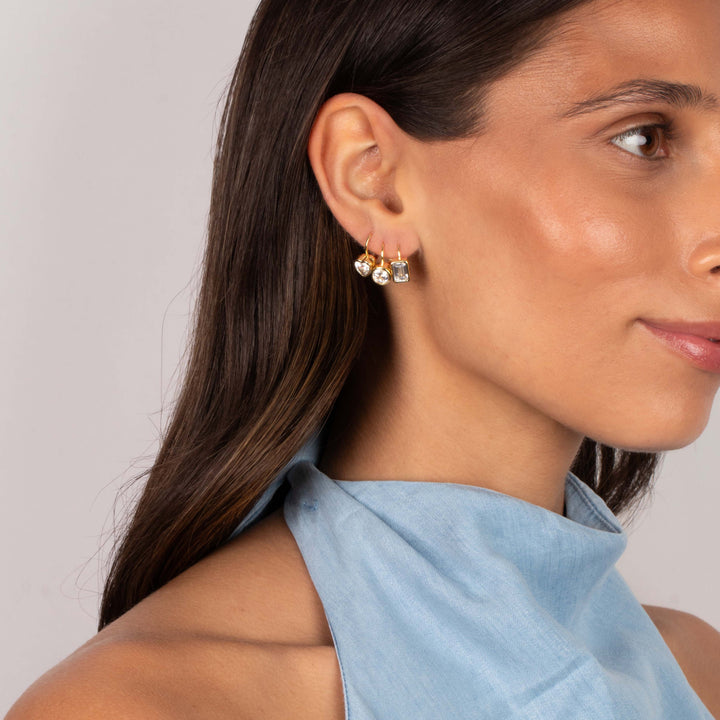 Close-up of a woman wearing gold and silver earrings with a light blue scarf.