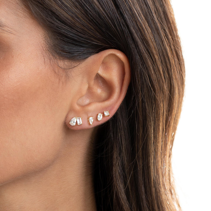 Close-up of a person wearing diamond stud earrings with a neutral background
