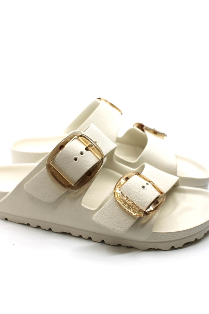 white waterproof sandals with 2 straps and large gold buckle closures.