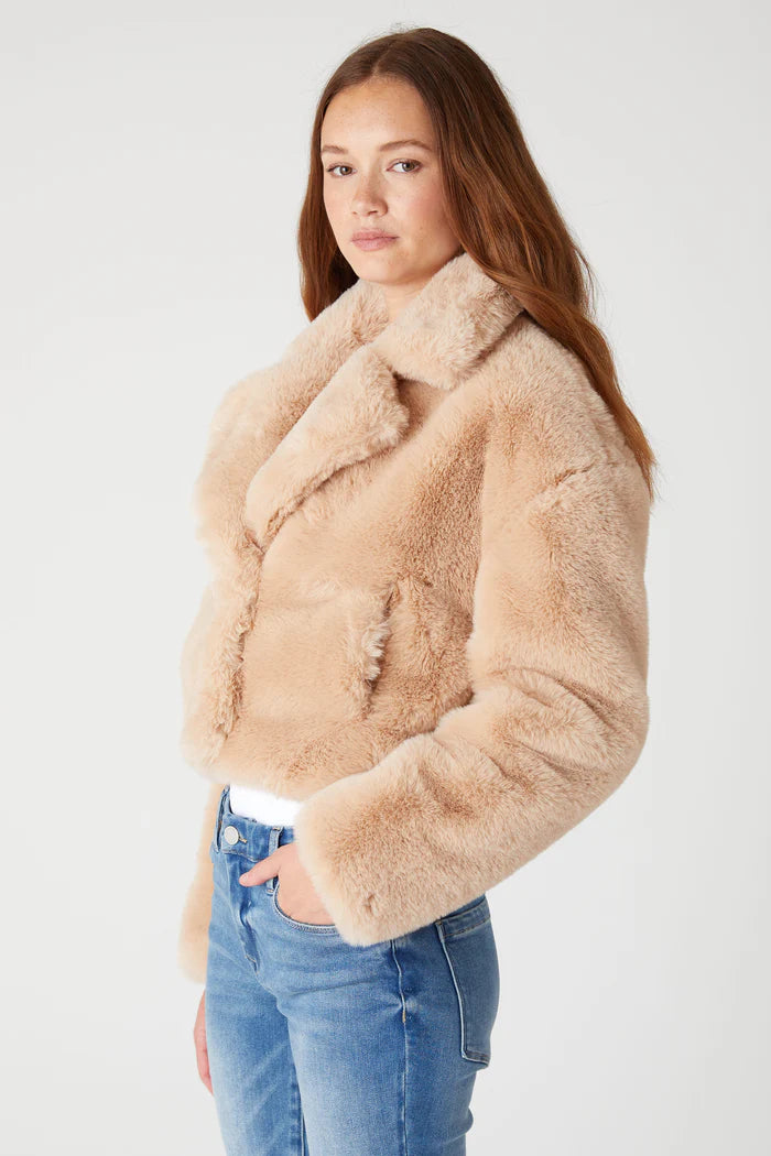 Woman wearing a beige sherpa jacket against a white background