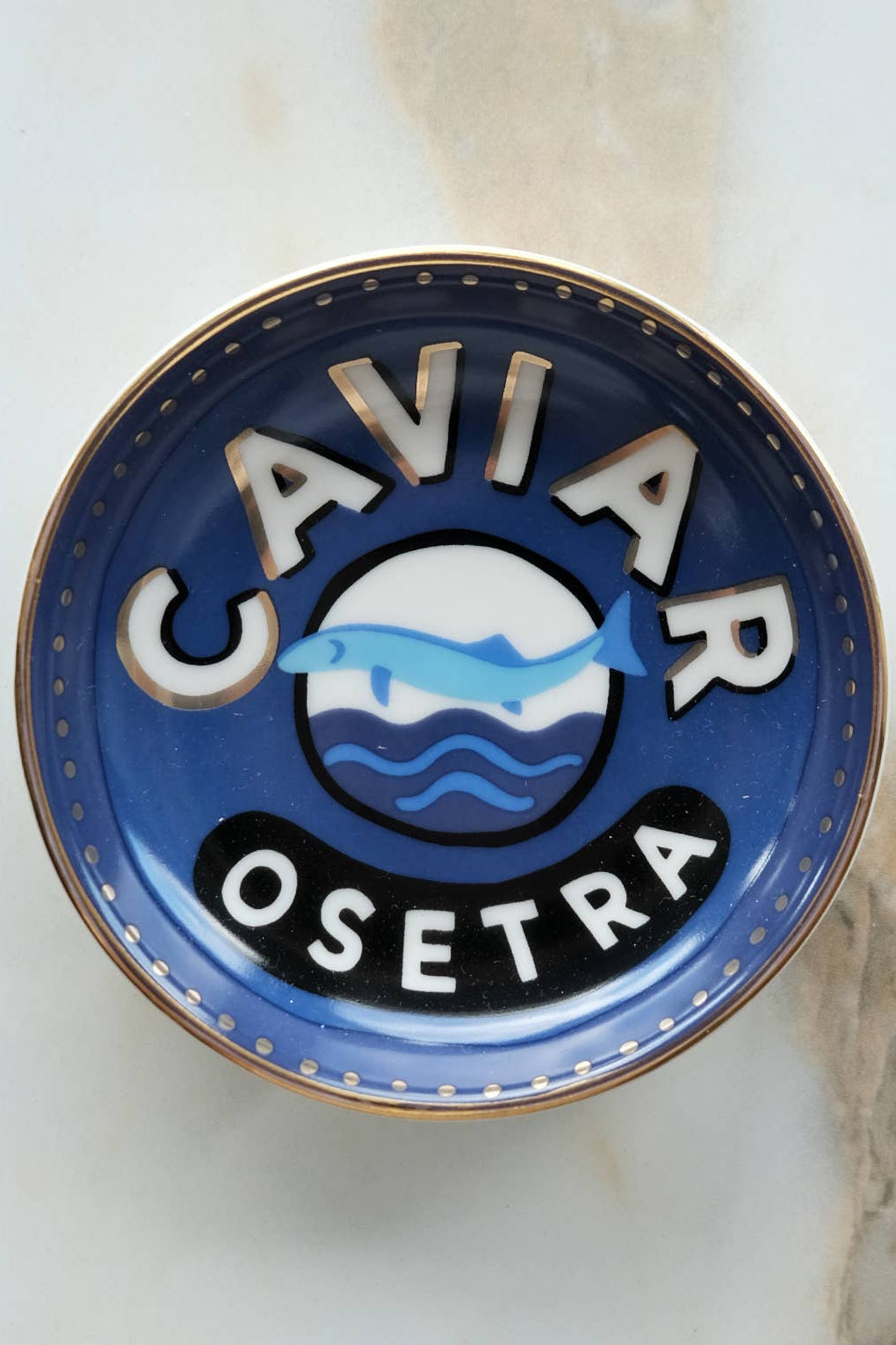 Caviar Osetra logo on a blue and gold plate with a marble background