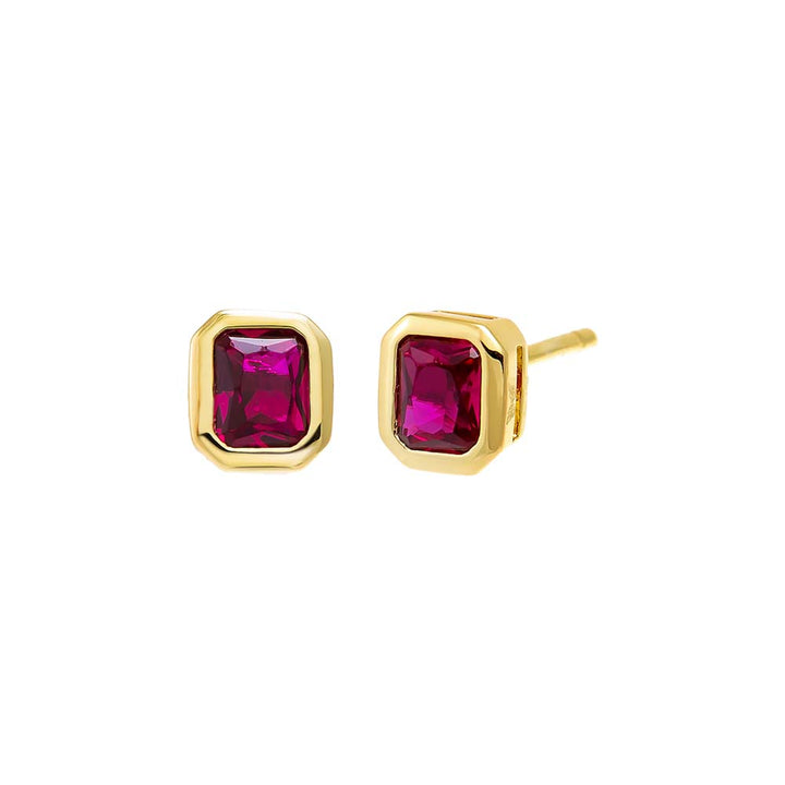 Gold earrings with red gemstones on a white background