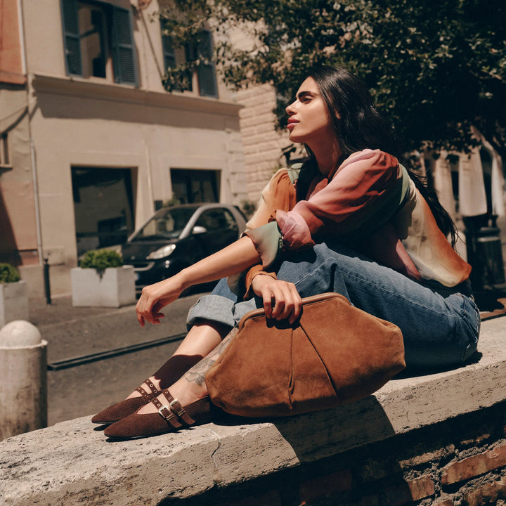 Woman sitting on a ledge with a brown bag in an urban setting