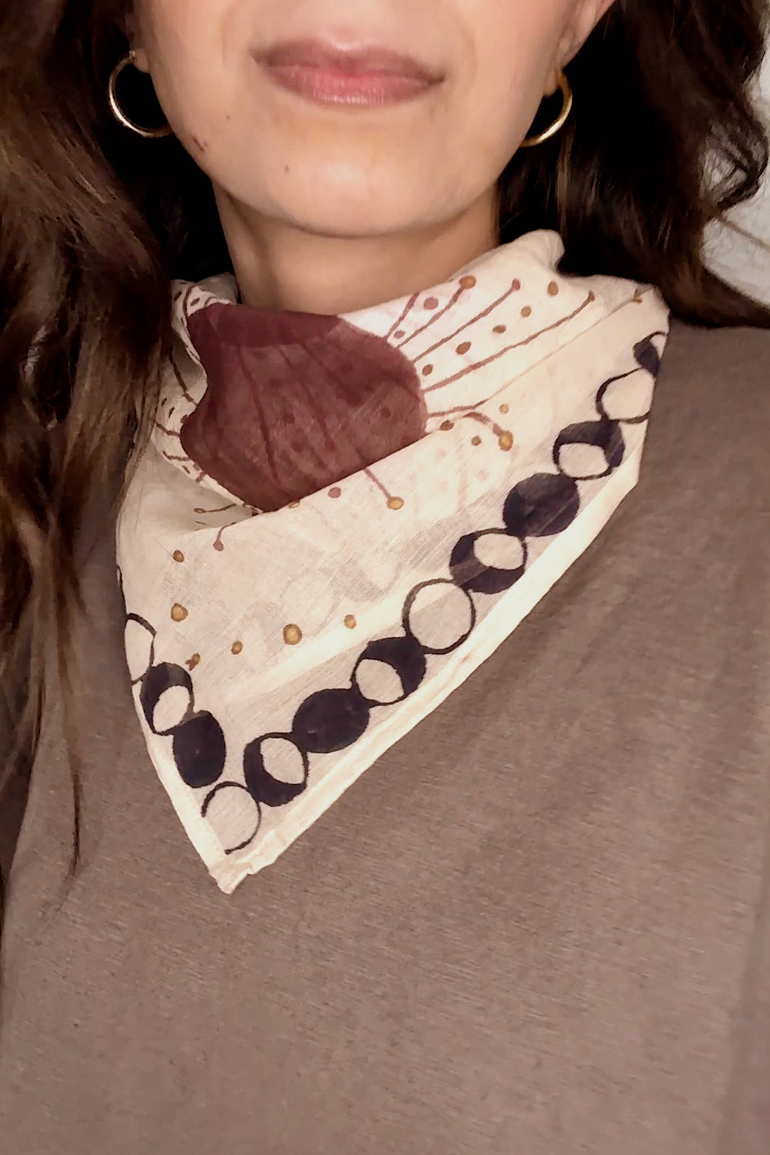 Person wearing a patterned scarf with a neutral background