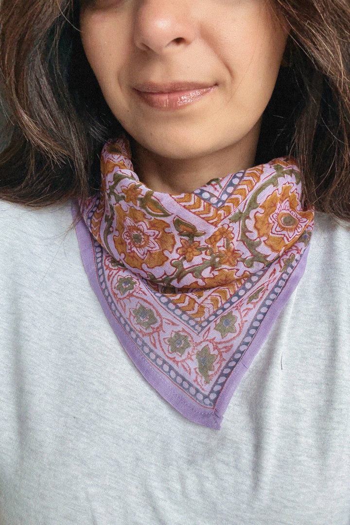 Woman wearing a colorful patterned scarf on her neck against a neutral background