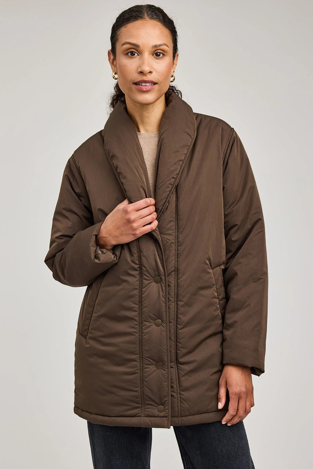 Woman wearing a brown puffer coat on a plain background
