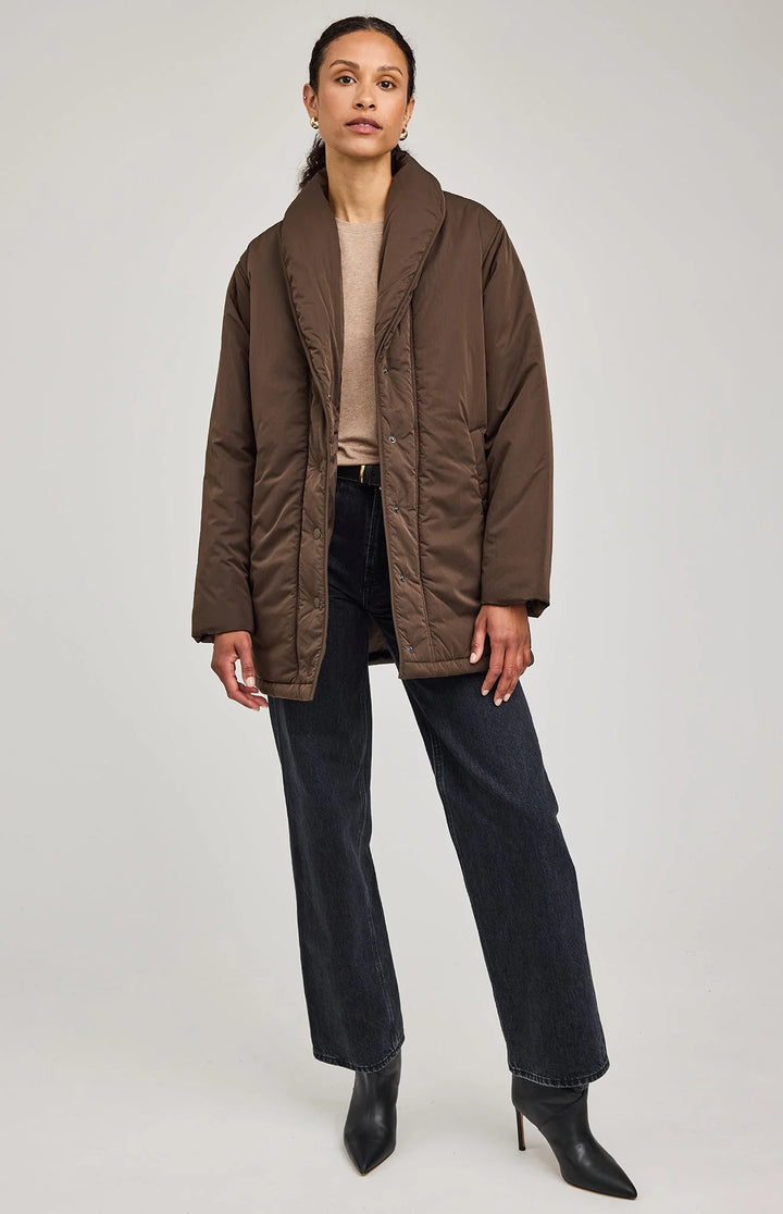 Woman wearing a brown quilted jacket on a white background