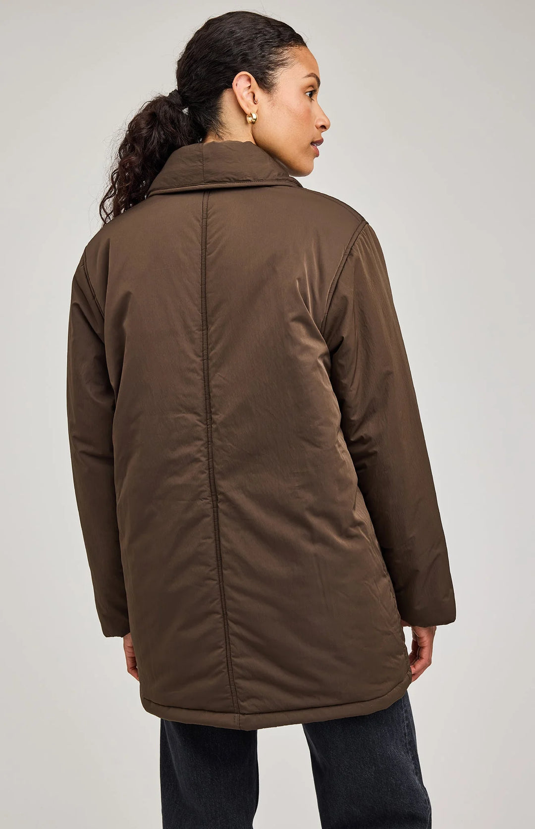 Woman wearing a brown coat against a plain background