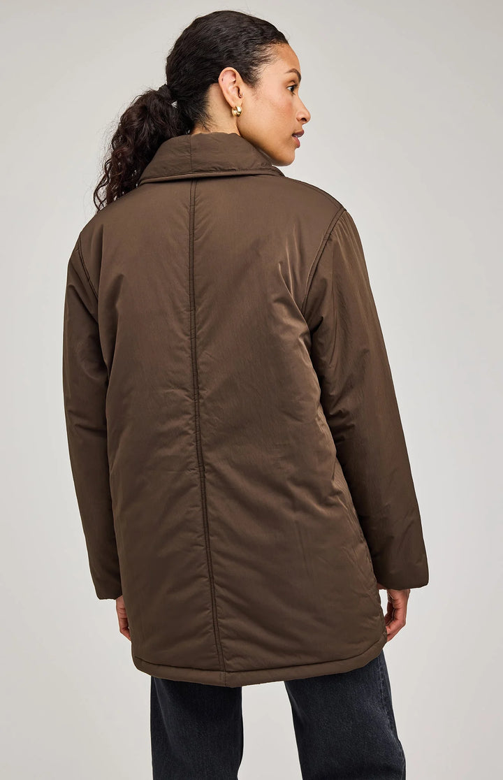 Woman wearing a brown coat against a plain background