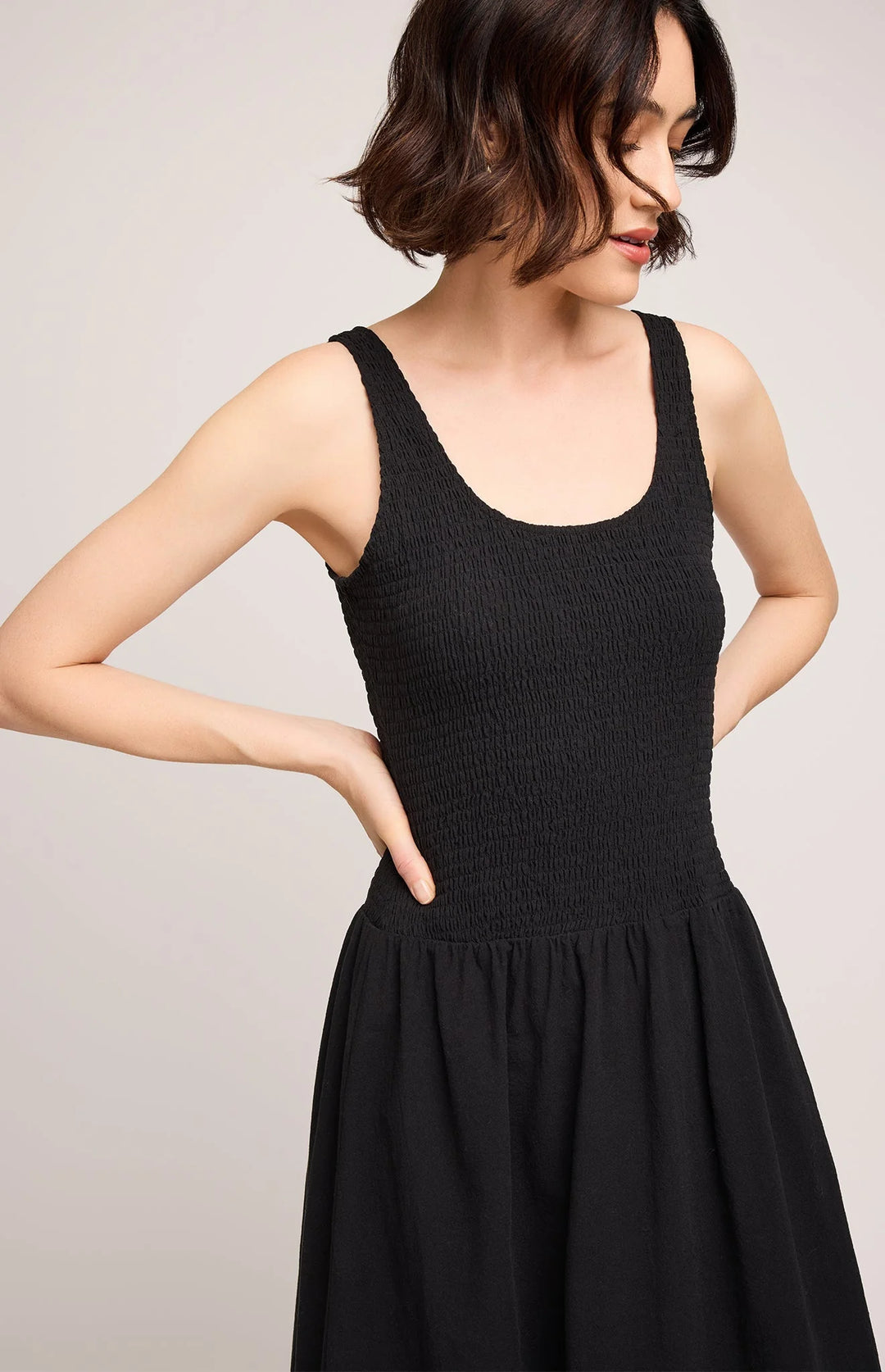 Woman wearing a black sleeveless dress against a plain background
