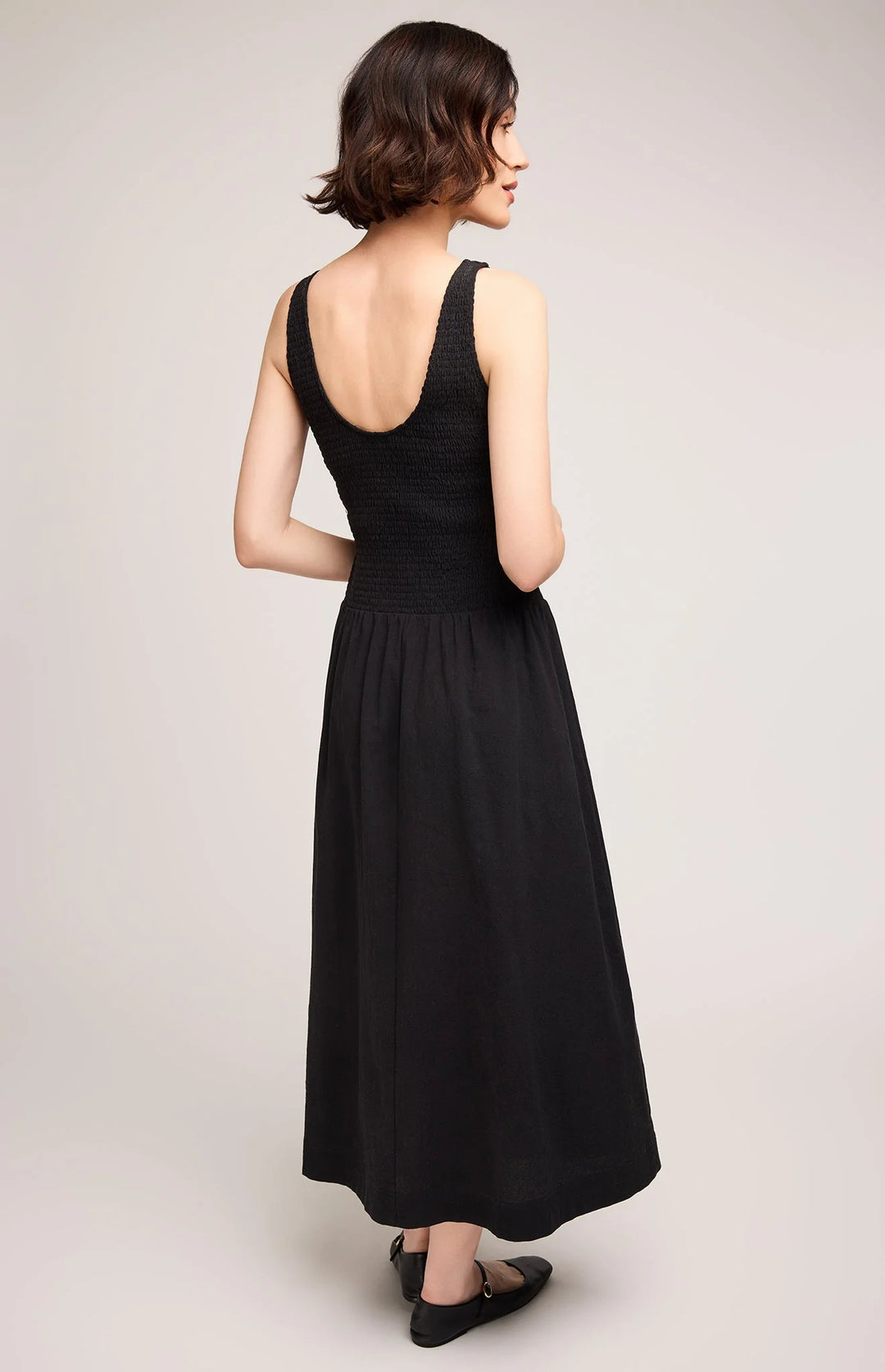 Woman wearing a black sleeveless dress on a plain background