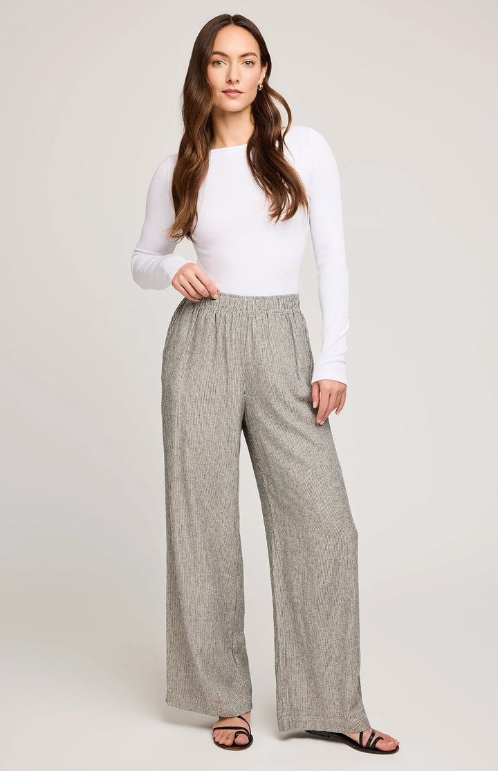 Woman wearing a white top and gray checkered pants on a plain background