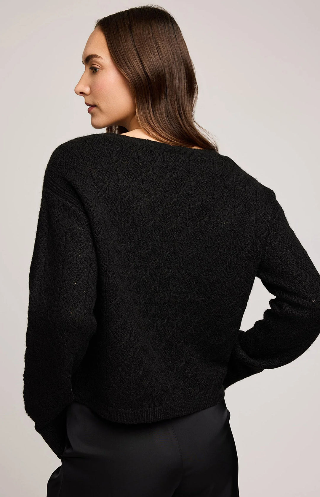 Woman wearing a black sweater against a plain background