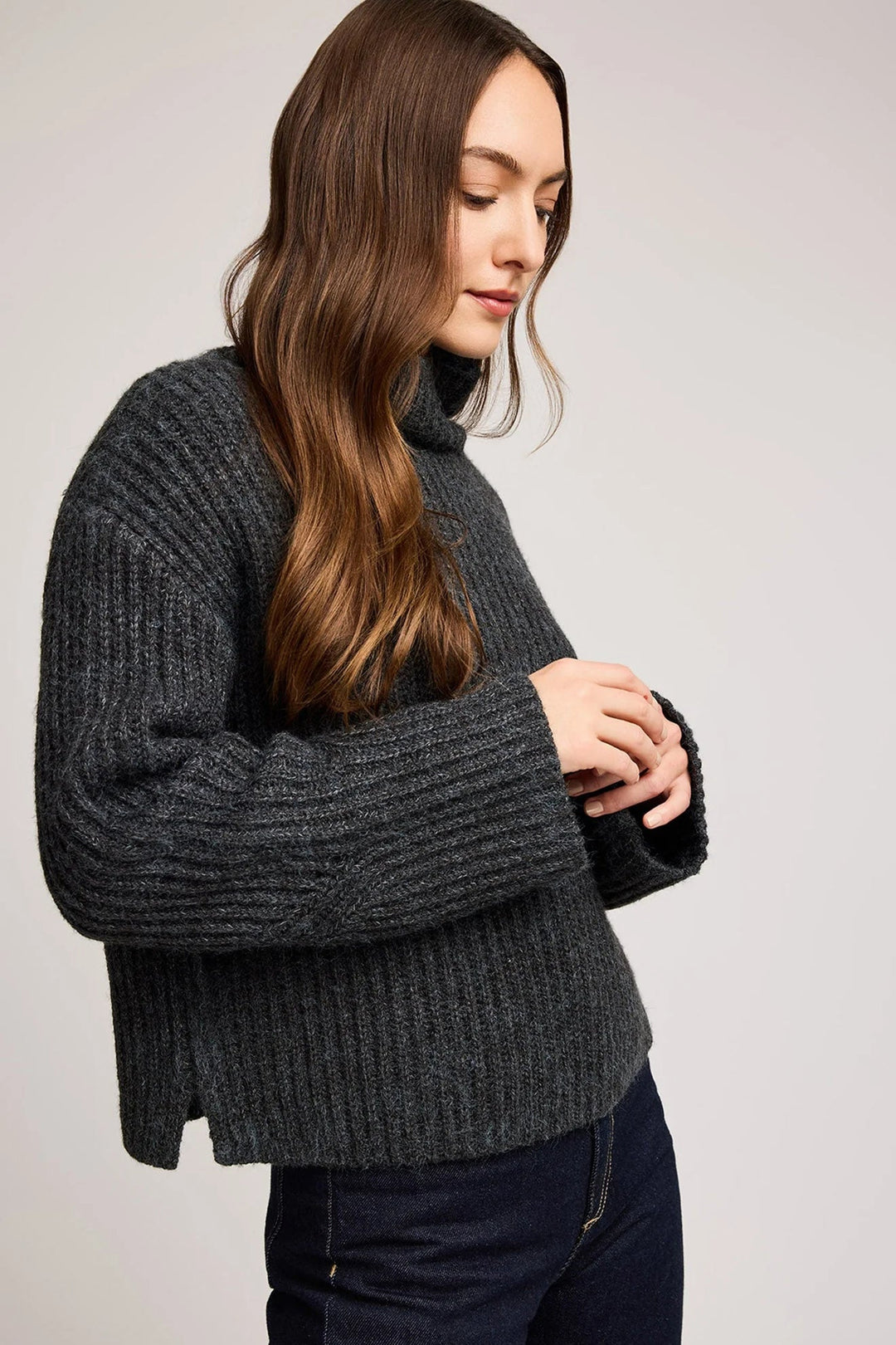 Woman wearing a dark gray ribbed sweater against a plain background