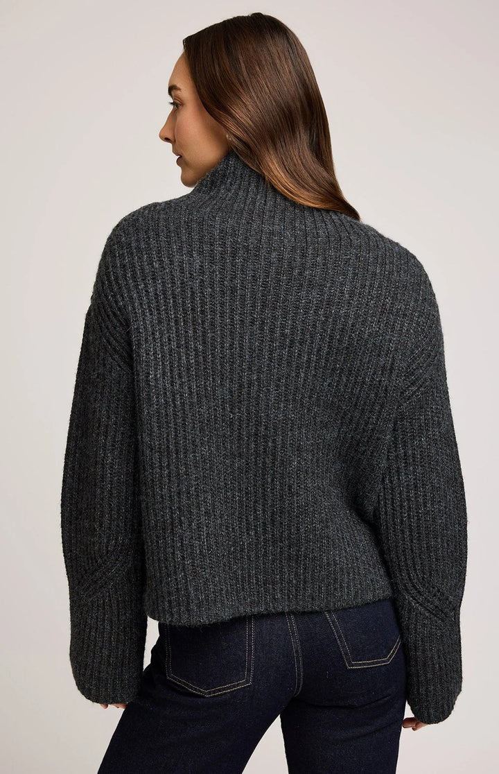 Person wearing a dark gray ribbed sweater on a plain background