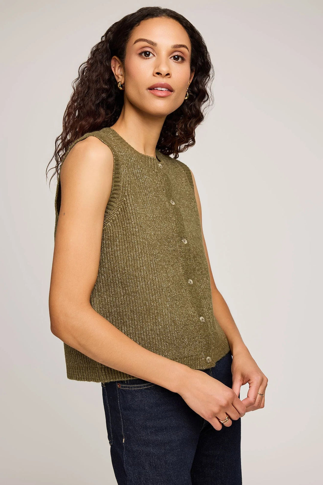 Woman wearing a green sleeveless knitted vest top against a plain background