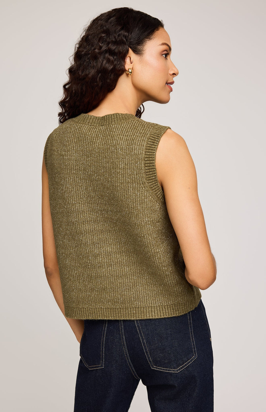 Woman wearing a green knitted vest against a plain background