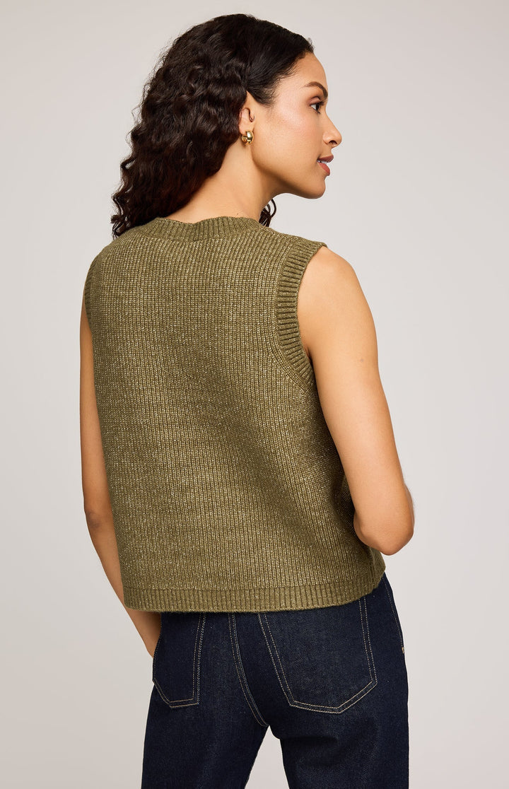 Woman wearing a green knitted vest against a plain background