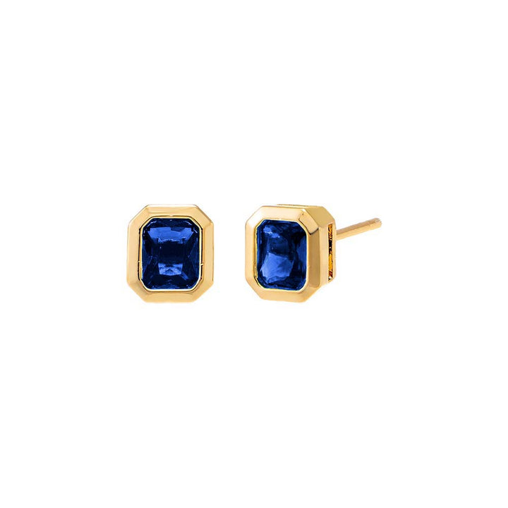 Gold earrings with blue gemstones on a white background