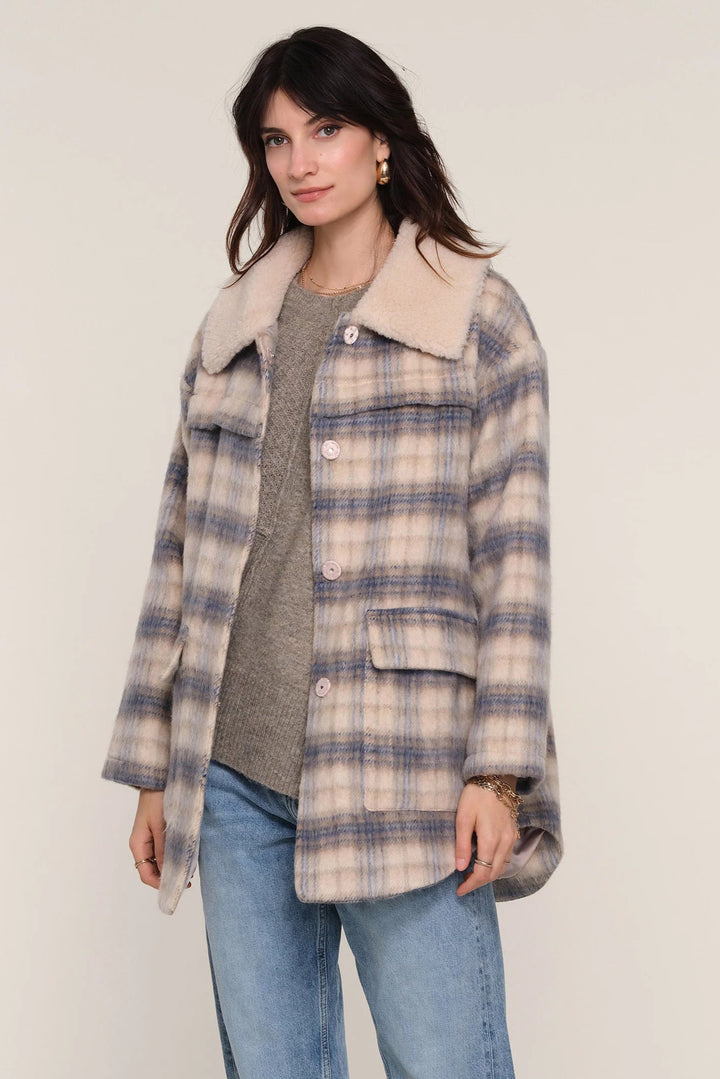 Woman wearing a plaid coat with a white collar on a plain background