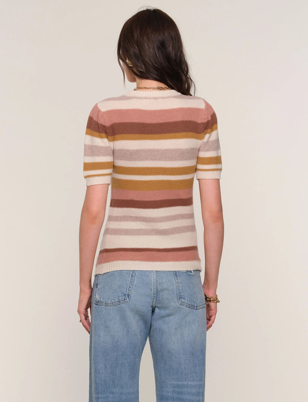 Person wearing a striped sweater and jeans on a plain background