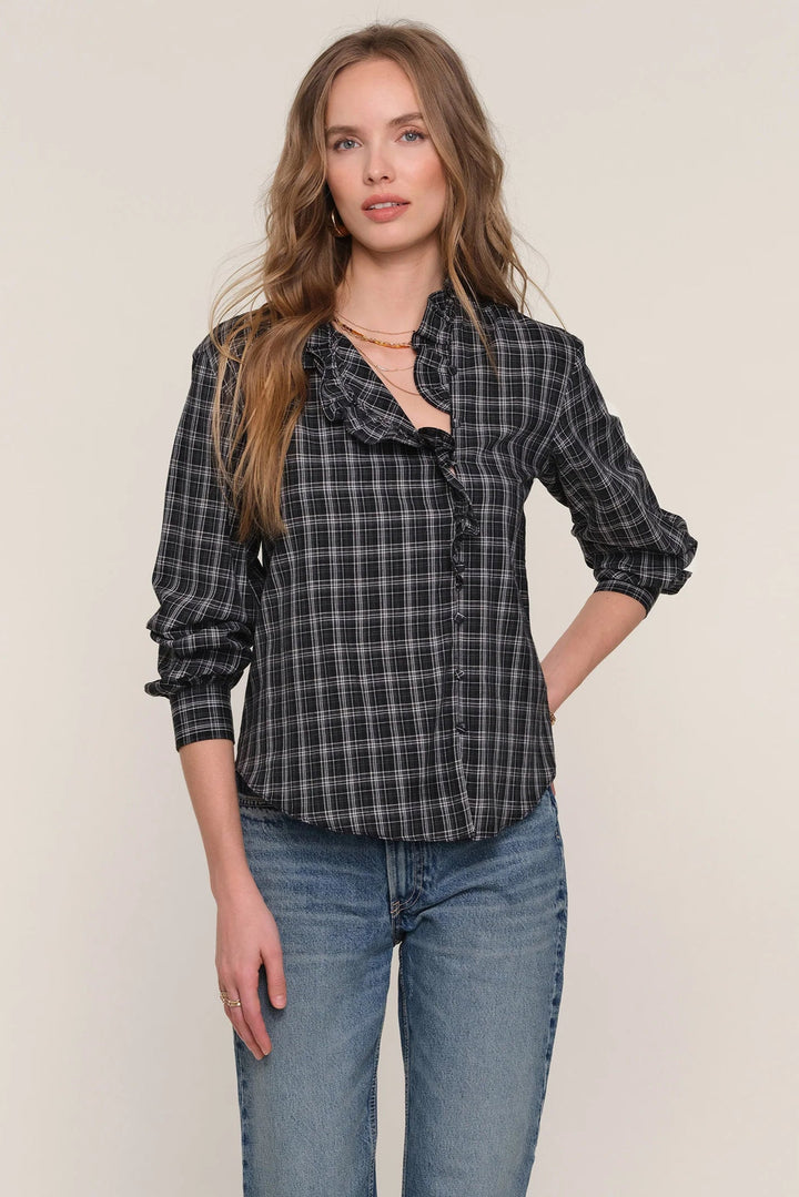 Woman wearing a plaid shirt and jeans against a plain background