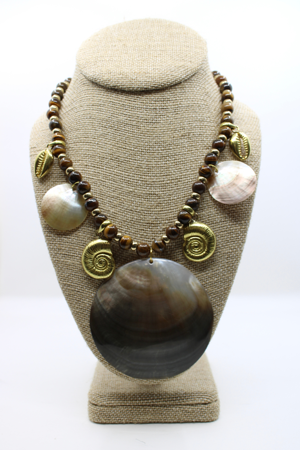 Necklace with large brown stone and pearls on a beige bust