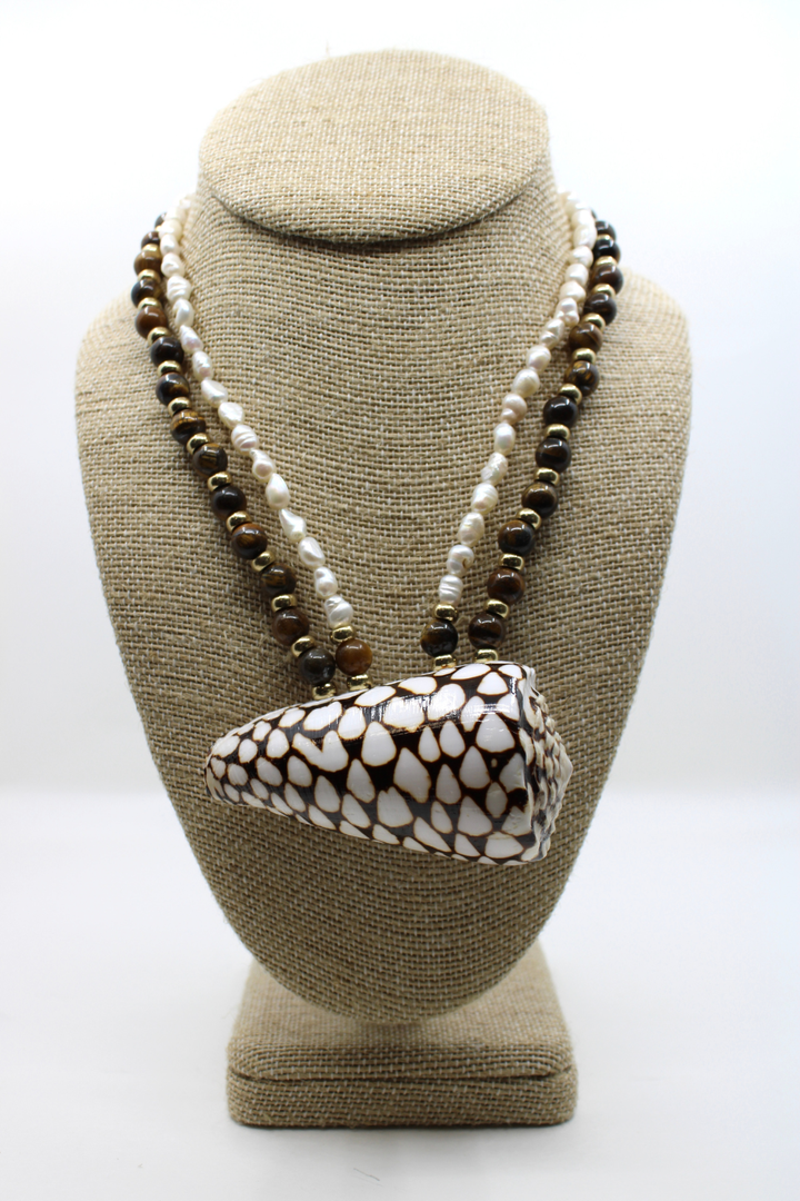 Necklace with a large shell pendant on a beige bust against a white background