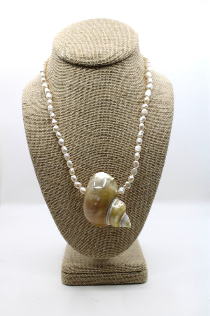 Necklace with a large shell pendant on a brown bust against a white background