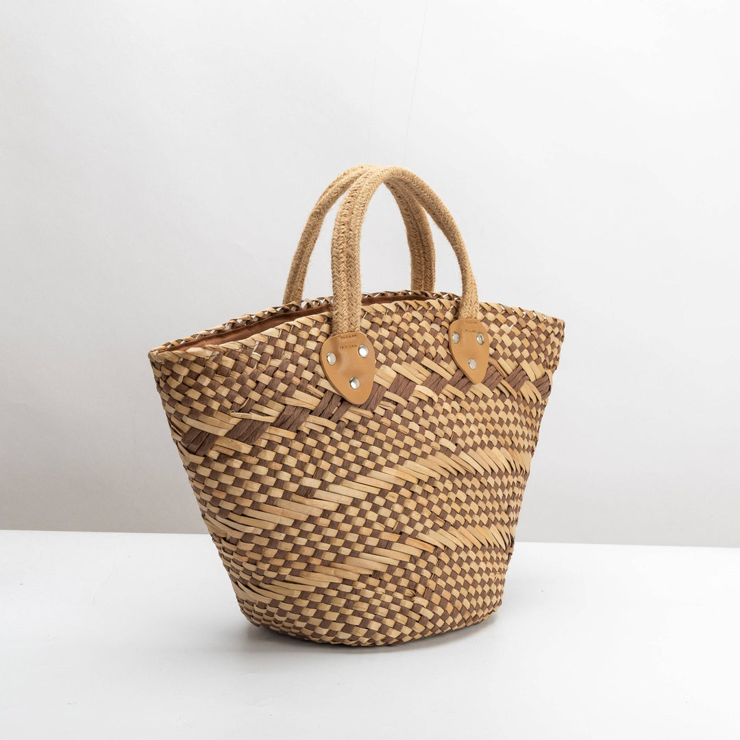 Woven basket with leather handles on a white background