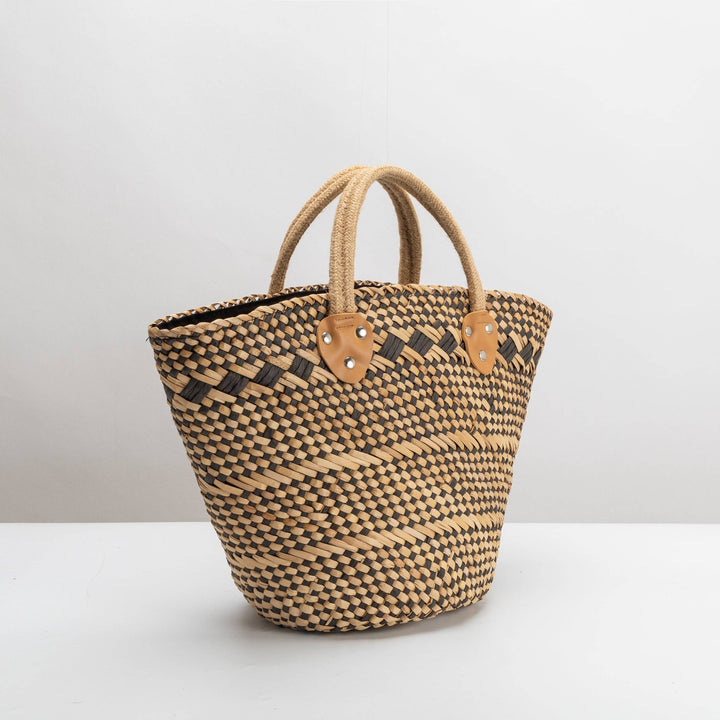 Woven straw bag with leather accents on a white background
