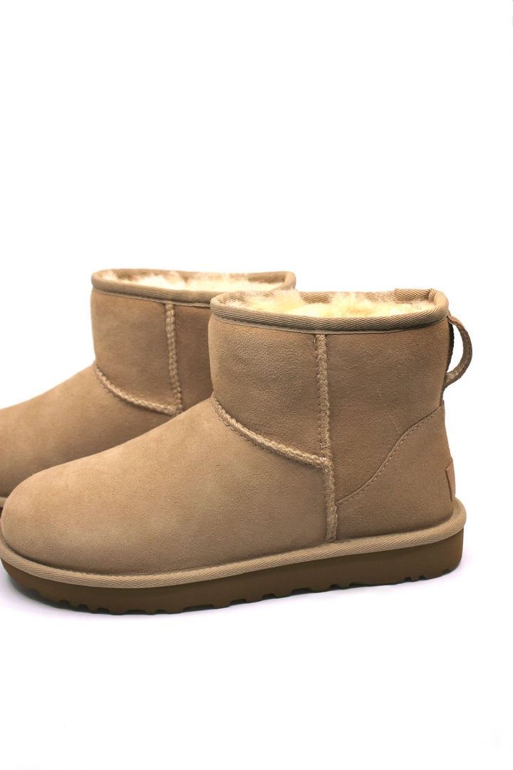 A pair of UGG Classic Mini II boots in color sand, featuring a low heel and a round toe.