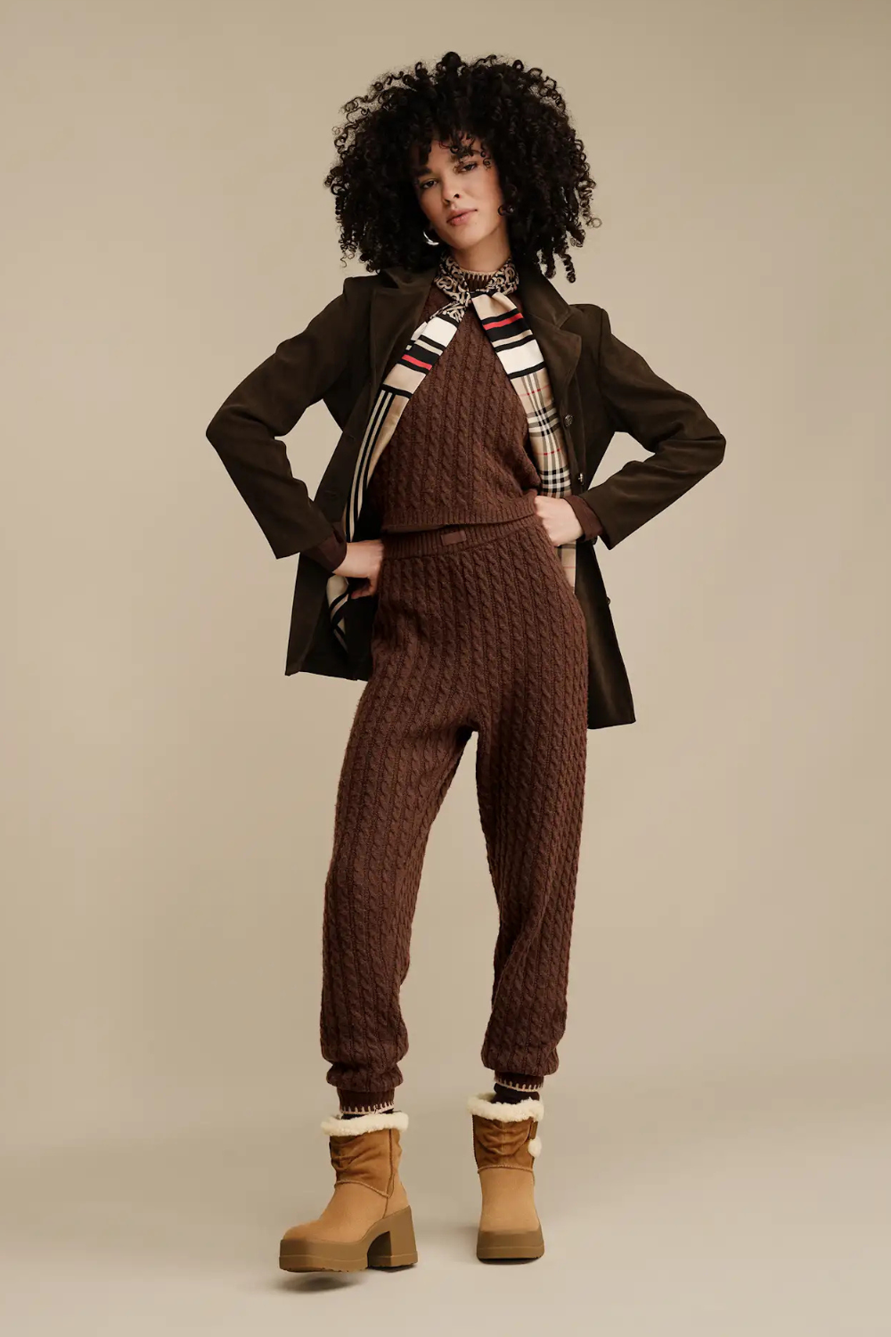 Woman wearing a brown outfit with a coat, sweater, and pants paired with ugg moxy Chelsea boot