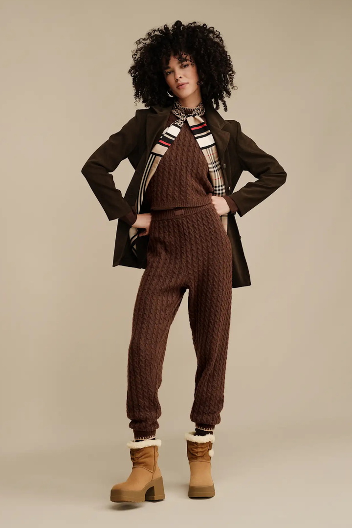 Woman wearing a brown outfit with a coat, sweater, and pants paired with ugg moxy Chelsea boot