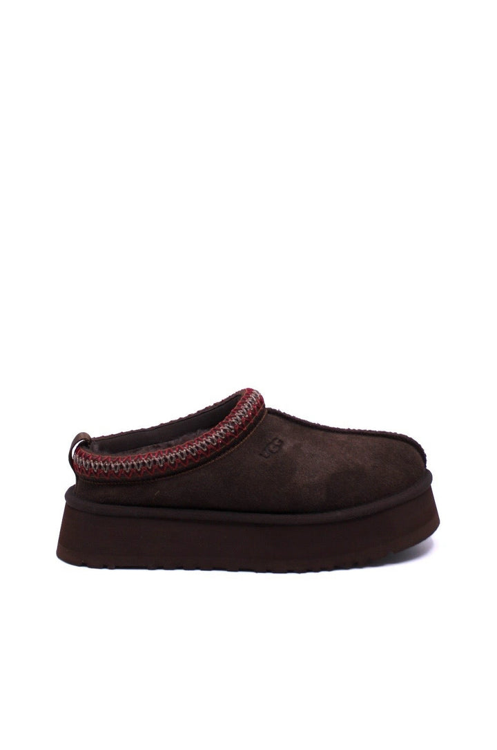 Pair of brown UGG slippers with red trim on a white background