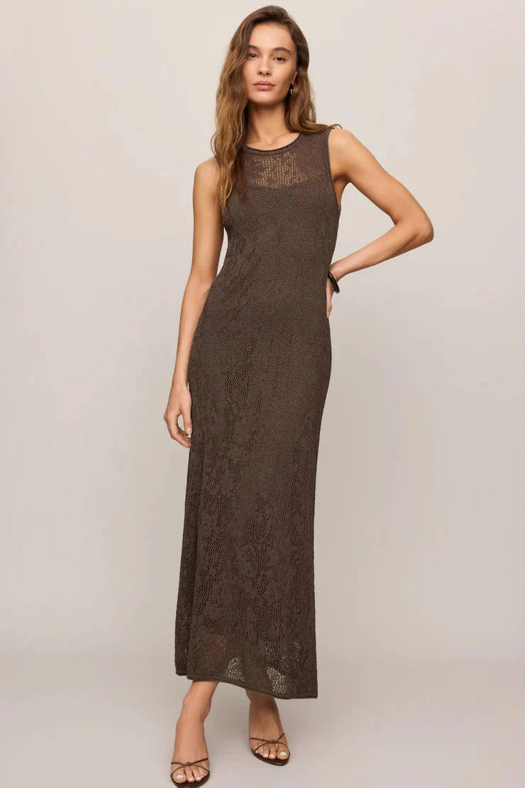 Woman wearing a brown sleeveless dress against a plain background