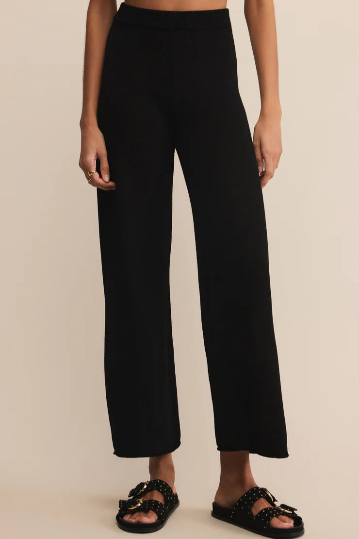 Person wearing black pants on a beige background