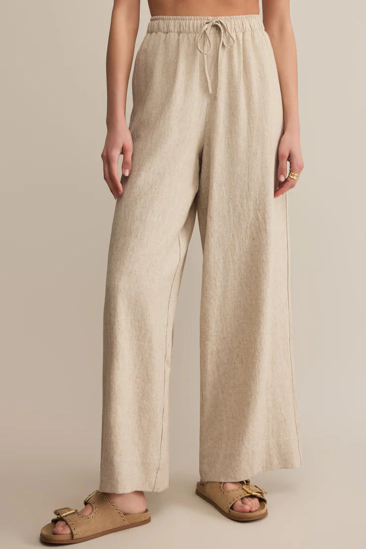 Beige linen pants worn by a person on a beige background