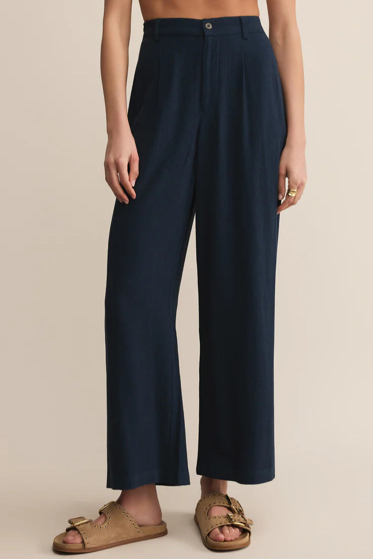 Navy blue wide-leg pants worn by a person on a beige background