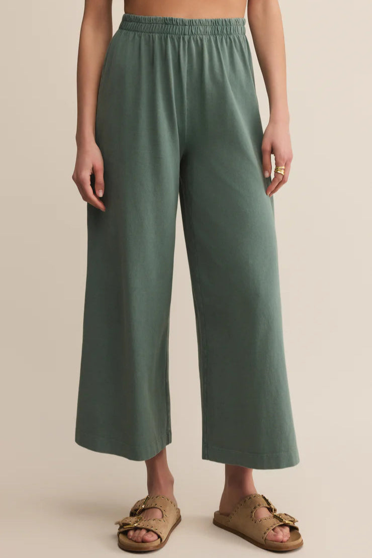 Person wearing green wide-leg pants on a beige background
