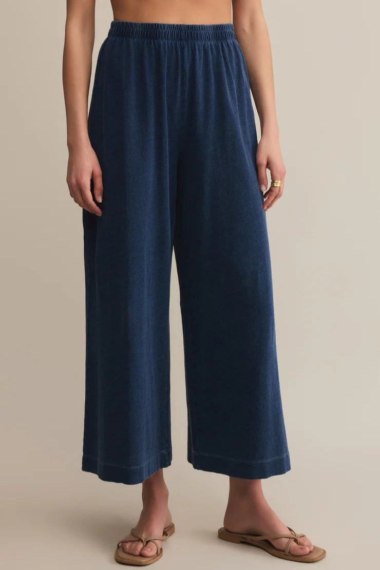 Navy blue wide-leg pants worn by a person on a beige background
