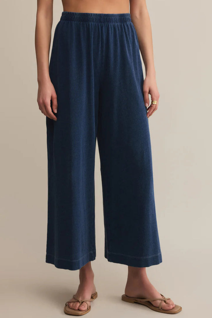 Navy blue wide-leg pants worn by a person on a beige background