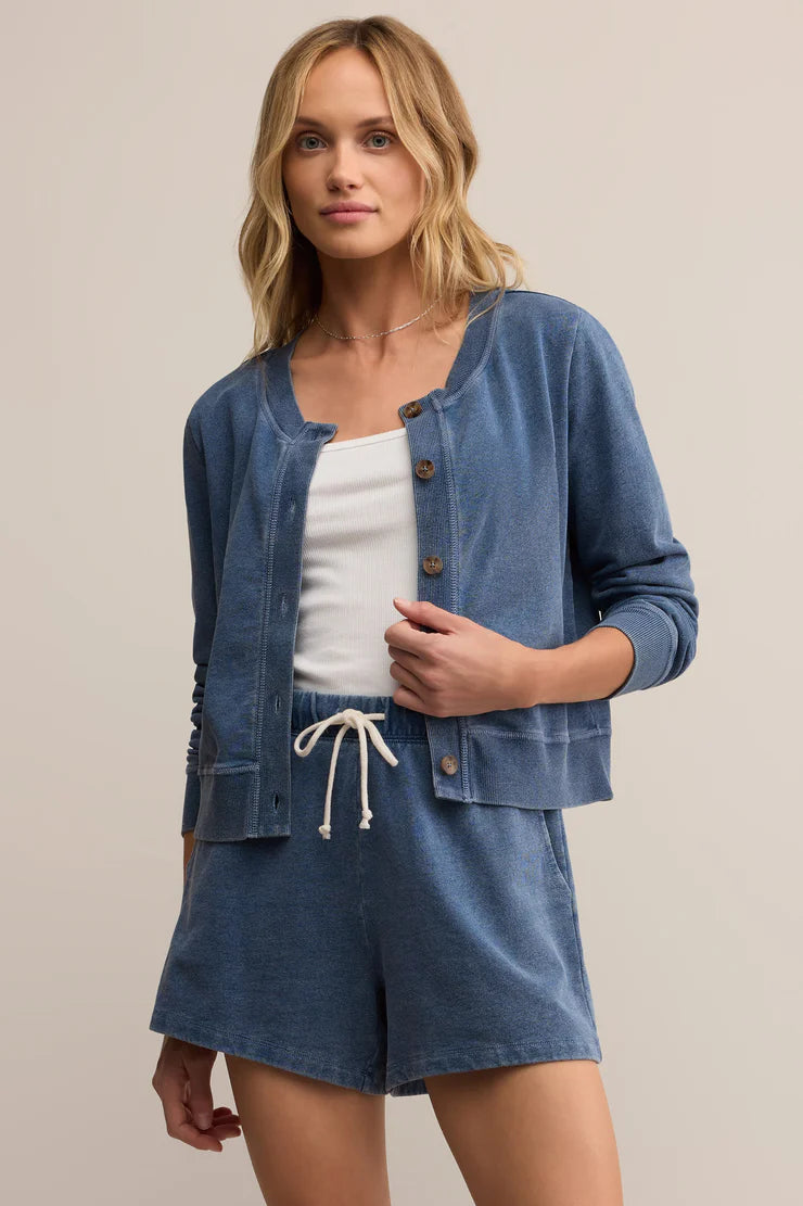 Woman wearing a denim cardigan and shorts set on a beige background