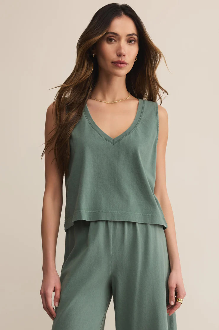 Woman wearing a green sleeveless top and pants against a beige background