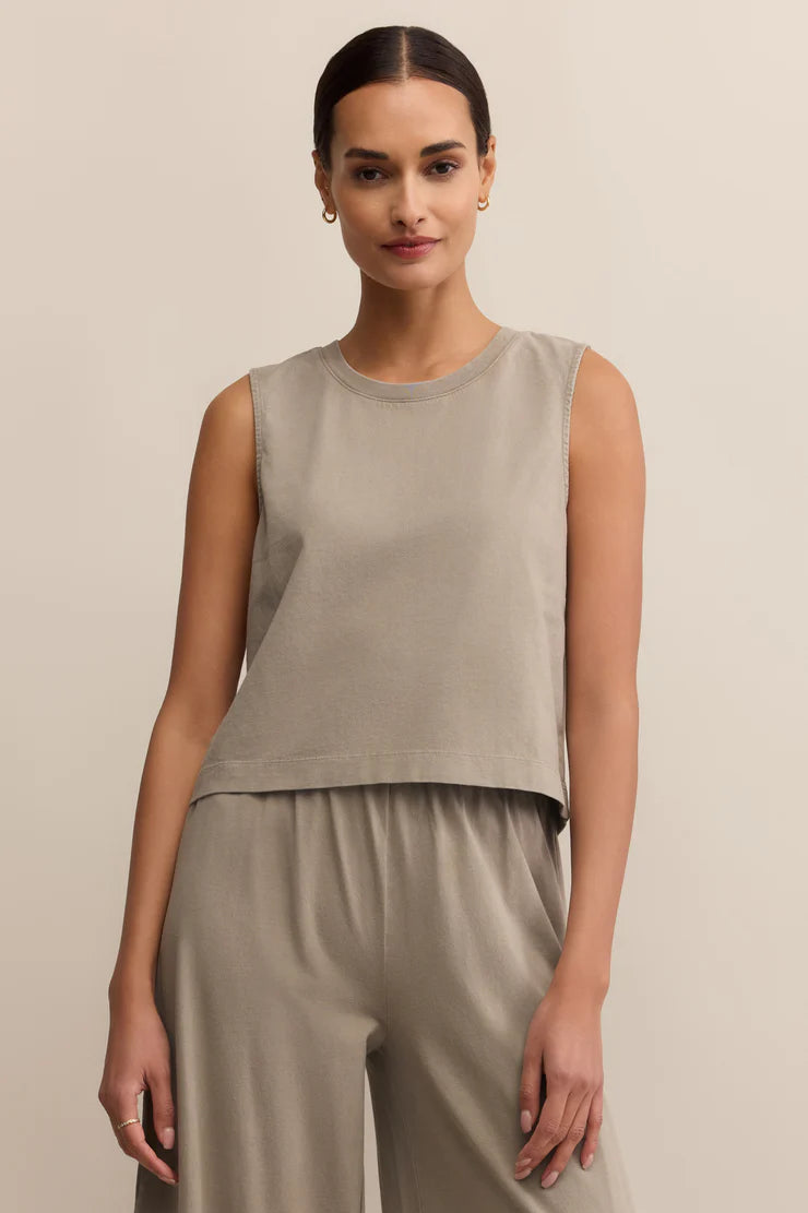 Woman wearing a beige sleeveless top and pants against a beige background