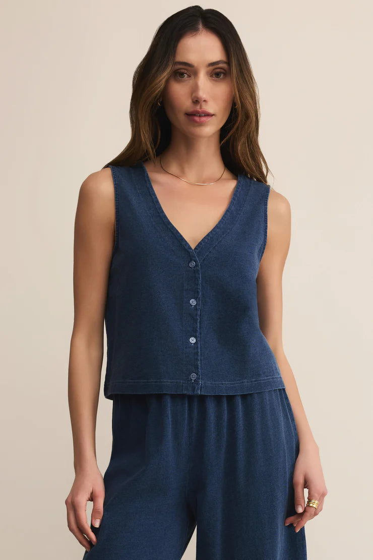 Woman wearing a blue sleeveless top and pants on a beige background