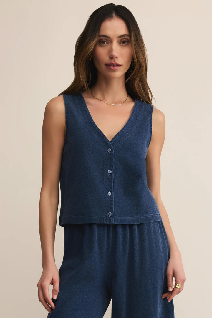 Woman wearing a blue sleeveless top and pants on a beige background
