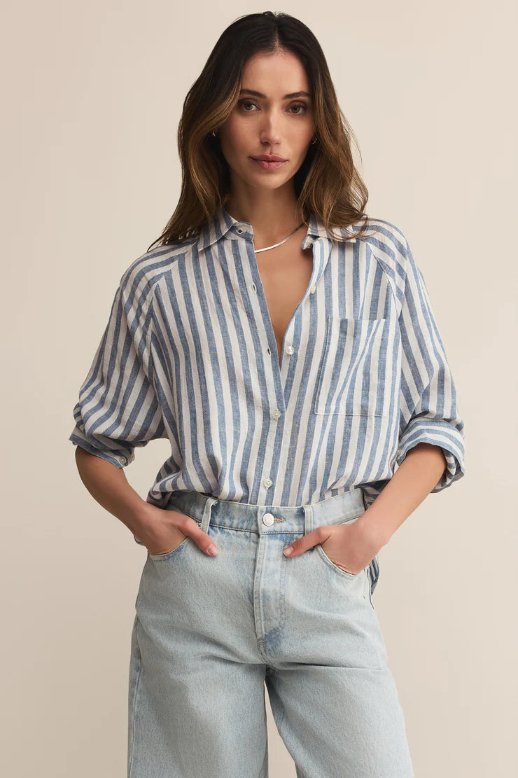 Woman wearing a striped shirt and jeans against a beige background