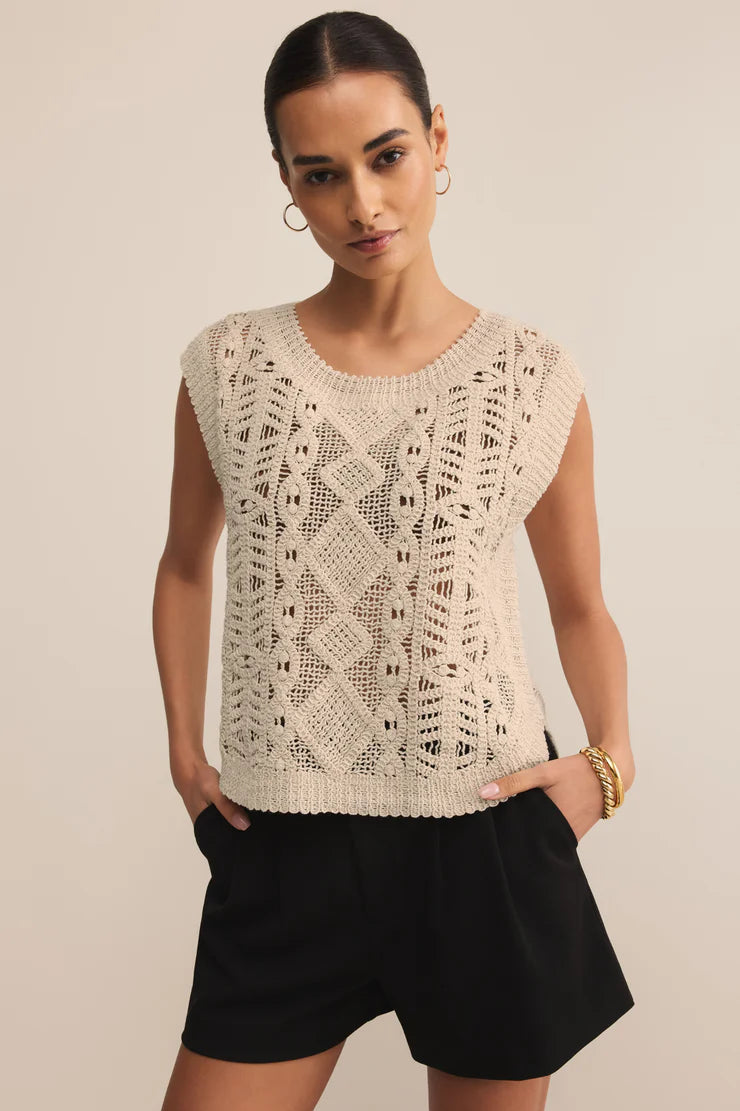 Woman wearing a sleeveless crochet top and black shorts against a beige background