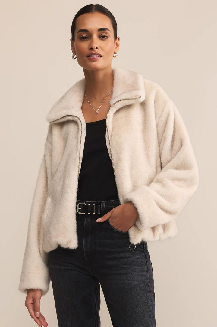 Woman wearing a cream fur coat against a beige background